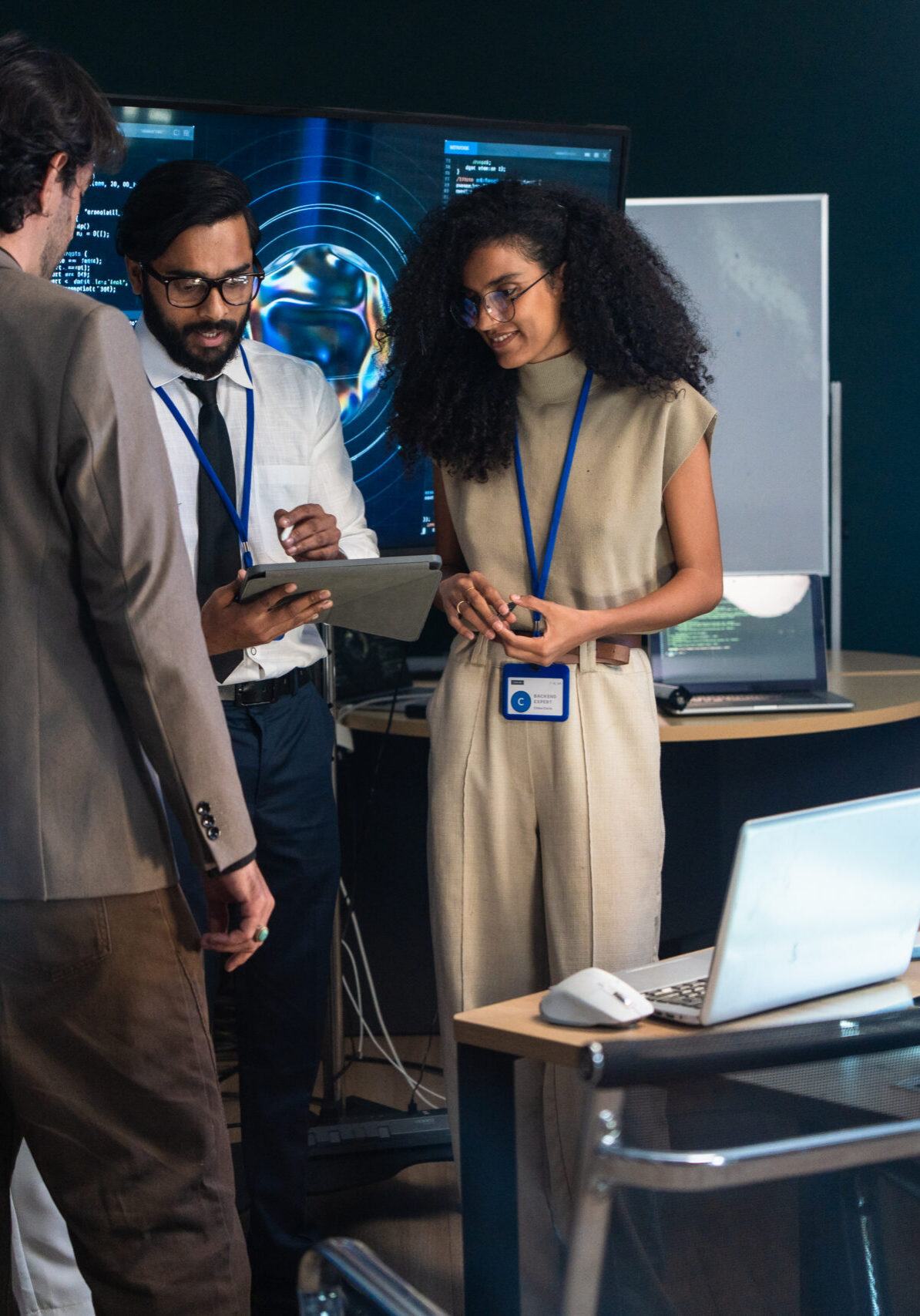 Tech team engineer discuss AI system data on tablet screen. Developer specialist analyze artificial intelligence software algorithm code near robotic hardware equipment in laboratory office meeting